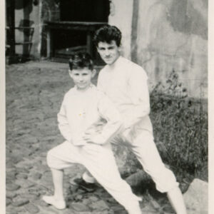 chłopiec i młody mężczyzna w strojach szermierczych przyjmujący pozycję do walki szermierczej