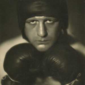 portret młodego mężczyzny w kasku bokserskim, trzymającego dłonie ubrane w rękawice bokserskie przy brodzie 