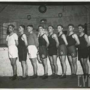 grupa młodych mężczyzn w strojach sportowych pozujących do zdjęcia na tle ringu bokserskiego