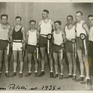 mężczyźni w sportowych strojach, część z nich ma widoczne na twarzy ślady walki, pozujący do fotografii