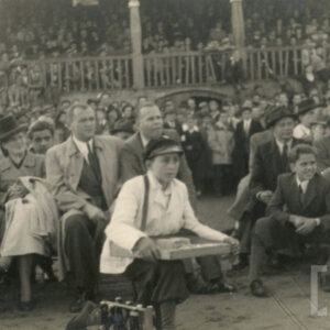 tłum ludzi, część siedzi na krzesłach nieopodal ringu, reszta na drewnianej trybunie stadionu