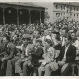 tłum ludzi, część siedzi na krzesłach nieopodal ringu, reszta na drewnianej trybunie stadionu