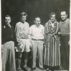 czterech mężczyzn stojących w szeregu na ringu, jeden z nich ubranych jest w bluzę klubową, inny w szlafrok