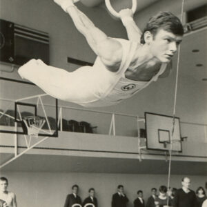 dobrze zbudowany mężczyzna w stroju sportowym, wiszący na kółkach gimnastycznych na sali sportowej