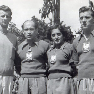 cztery osoby - jedna kobieta i trzech mężczyzn, pozujący do fotografii w sportowych dresach