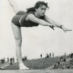 młoda, wysportowana kobieta w stroju sportowym ćwicząca na równoważni, na tle trybun stadionu