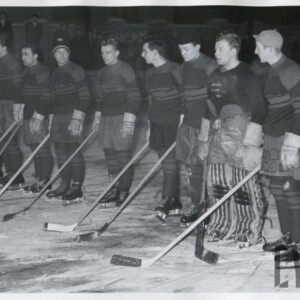 grupa mężczyzn stojących w rzędzie na lodowisku, ubranych w stroje do gry w hokeja na lodzie