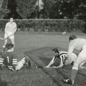 mężczyźni w strojach sportowych, trzymający laski hokejowe, grający na trawiastym boisku