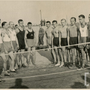 kilkunastu mężczyzn w strojach sportowych stojących na prowizorycznym ringu otoczonym linami