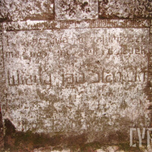 zabrudzona i omszała, kamienna tablica z niewyraźnymi napisami