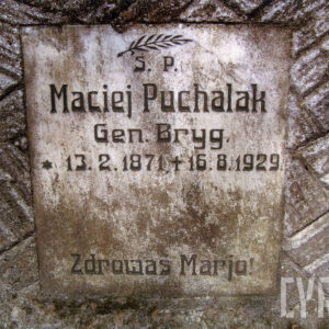 zabrudzona tablica z napisami i liściem palmowym w górnej części wtopiona w płytę nagrobną