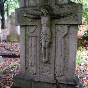 szeroka płyta nagrobna o ściętych górnych narożach z dużym krzyżem łacińskim o porowatej powierzchni i płaskorzeźbą Chrystusa