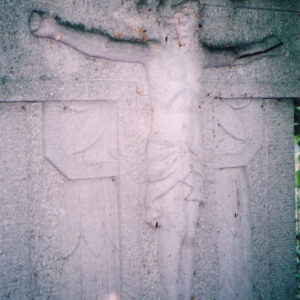 figura Chrystusa w koronie cierniowej na krzyżu płaskorzeźbiona na płycie nagrobnej