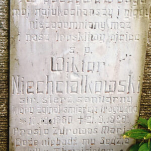 biała tablica z wyrytymi napisami wtopiona w płytę nagrobną