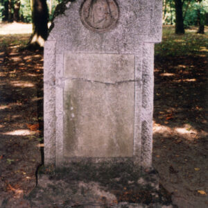 płyta nagrobna umocowana na cokole z wtopionym krzyżem łacińskim z tablicą epitafijną i tondem z płaskorzeźbioną głową Matki Boskiej