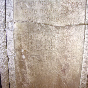 pęknięta poziomo biała tablica epitafijna z zamazanymi napisami wtopiona w płytę nagrobną