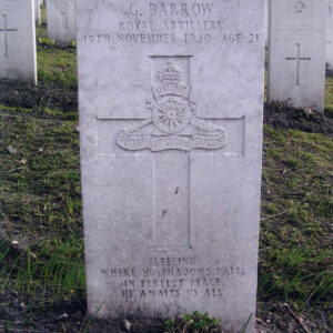 biała, pionowa płyta nagrobna z wyżłobionym krzyżem łacińskim, pośrodku którego wyryto znak Pułku Reflektorów, za nią inne nagrobki i drzewa