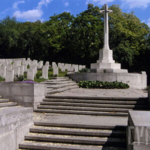 Kilka szeregów stopni prowadzących do Krzyża Poświęcenia oraz nagrobków. Z tyłu drzewa liściaste.