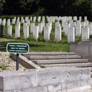 Schody prowadzące do rzędów nagrobków o jednolitym wyglądzie. Przy schodach mur z wyżłobionymi datami.