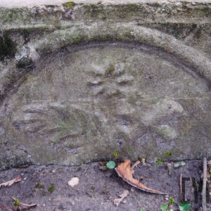 element obmurowania, profilowane półkole z przedstawieniem krzyża, liścia palmowego oraz kwiatu