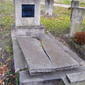 pionowa płyta nagrobna osadzona na cokole ze szklaną, czarną tablicą inskrypcyjną, płyta nakrywająca mogiłę ziemną pęknięta na całej długości