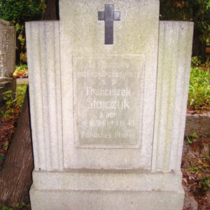 pionowa płyta z krzyżem łacińskim i tablicą epitafijną, po jej bokach dwa żłobione pionowo słupki, z tyłu teren cmentarza