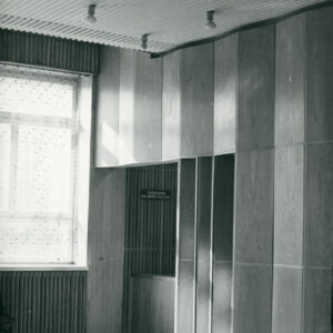 fragment jasnej sali z plafonem na suficie i małym bufetem za harmonijkowymi drzwiami