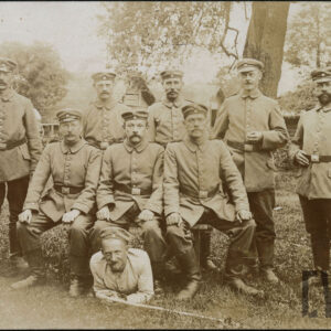 grupa mężczyzn w pruskich mundurach roboczych pozująca do zdjęcia na tle drzew, jeden z nich leży, trzech siedzi, pozostali stoją