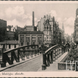 most z żelaznymi przęsłami, przed nimi dwie latarnie uliczne, w głębi ulica, na jej narożnikach okazałe ozdobne kamienice, z lewej zabudowania fabryczne nawiązujące do architektury wojskowej 