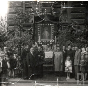 grupa ludzi stoi na tle ołtarza z obrazem z wizerunkiem Jezusa, za ołtarzem fragment kamienicy