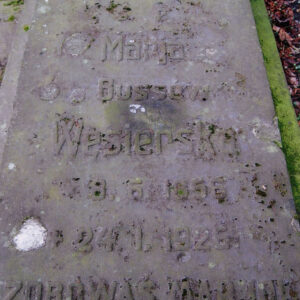 Płyta nagrobna z inskrypcją i krzyżem łacińskim pokryta białym i zielonym nalotem.