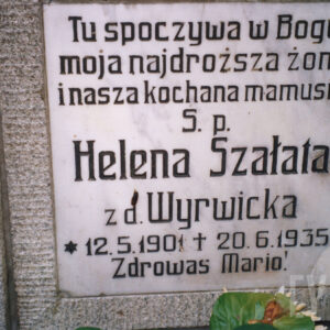 biała, kwadratowa tablica z czarnymi napisami umocowana do płyty nagrobnej