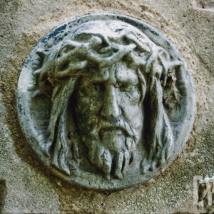 płaskorzeźba z głową Chrystusa w cierniowej koronie umocowana do kamiennej płyty nagrobnej