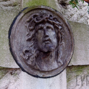 tondo z głową Chrystusa w koronie cierniowej na krzyżu łacińskim wtopionym w płytę nagrobną