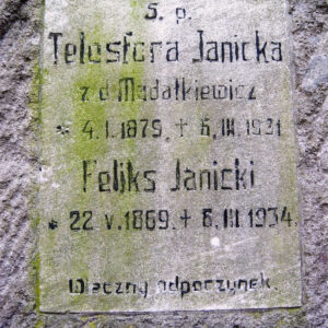 prostokątna tablica z napisami wtopiona w płytę nagrobka, pokryta zielonym nalotem