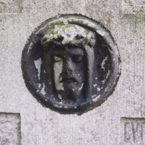 zniszczony, z odpadającą farbą okrągły medalion z wyobrażeniem głowy Chrystusa w koronie cierniowej