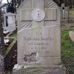 pionowa, prostokątna tablica zamknięta na górze łukiem, osadzona na cokole, w jej dolnej części, odciętej ukośną nieregularną linią na wzór skały, wyryty napis epitafijny, z lewej duży ubytek na licu, w górnej części płaskorzeźbiony krzyż na tle promienistej glorii, na przecięciu ramion krzyża tondo bez medalionu, w głębi kamienne nagrobki