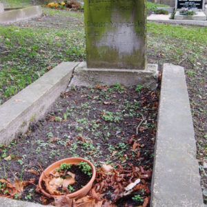 mogiła ziemna otoczona kamiennym niskim murkiem, w części zagłówkowej prostokątna pionowa płyta kamienna zamknięta łukiem, na licu ryty napis, z pozostałością czarnego barwnika, całość pokryta zielonym nalotem, w głębi kamienne nagrobki