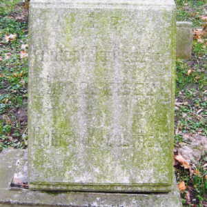 tablica inskrypcyjna ustawiona na prostokątnym postumencie, oparta na konsoli i pokryta zielonym nalotem