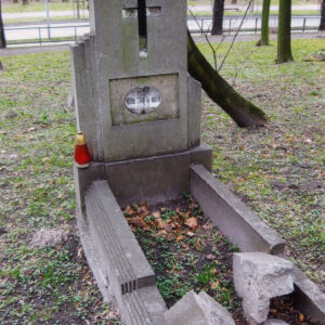 mogiła ziemna obramowana uskokowym murkiem, w części zniszczonym, u wezgłowia wysoka stela osadzona na prostopadłościennym cokole, złożona z pionowo ustawionej prostokątnej płyty o ściętym schodowo górnym lewym narożu, po jej bokach dwa, wąskie skrzydła obniżające się schodkowo, lewe z nich wyższe, pośrodku płyty, nad płyciną łaciński krzyż z czarnego szkła (częściowo uszkodzony), w płycinie wtórnie zamontowana blaszana, owalna tabliczka epitafijna z czarnym napisem na białym tle
