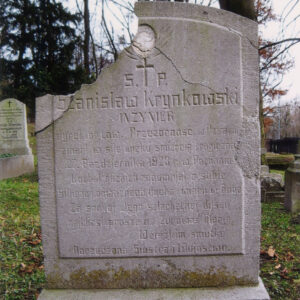 stela w formie stojącego prostokąta zakończona zamkniętym łukiem, z lica lekko wystająca tablica z wyrytym napisem, nad inskrypcją ślad po okrągłym medalionie, stela odłamana w lewym górnym narożu, pęknięcia na prawej krawędzi, w głębi drzewa