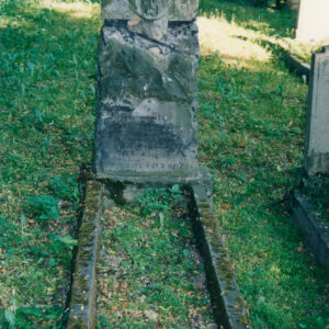 nagrobek w formie steli z wtopionym krzyżem i medalionem z głową Chrystusa