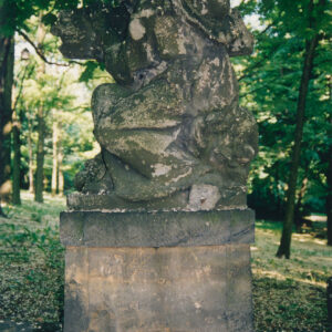 pomnik mężczyzny w długiej szacie, z kapeluszem na plecach obejmującego krzyż stojący na postumencie