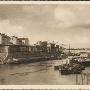 na obu brzegach rzeki zacumowane barki, w głębi budynki i żurawie portowe, z prawej most żelazny