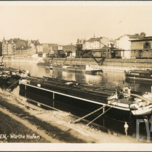 na obu brzegach rzeki zacumowane barki, w głębi zabudowa portowa i żurawie portowe, z lewej wysokie kamienice