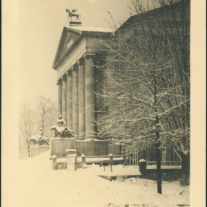 neoklasycystyczny budynek z sześciokolumnowym portykiem, zwieńczony rzeźbą konia ze skrzydłami przed portykiem, na cokołach rzeźby po obu stronach zaśnieżonych schodów, z prawej drzewo bez liści