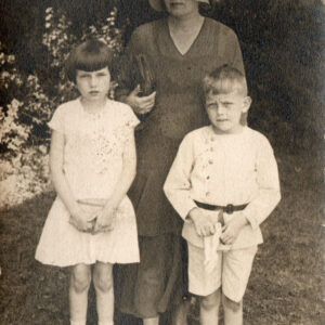 kobieta w kapeluszu  i dwoje dzieci, dziewczynka i chłopiec, stoją na tle zieleni