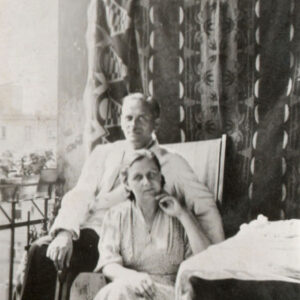 kobieta i mężczyzna siedzą na fotelu na balkonie, za nimi wzorzysta zasłona