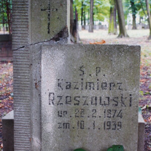 stela złożona z prostokątnej płyty, wtopionej lewą krawędzią w wyższy prostopadłościenny słup, pokryty poziomym żłobkowaniem, powyżej wyryty u góry krzyż łaciński, na tablicy inskrypcja, krzyż i litery wypełnione czarnym barwnikiem