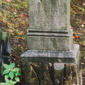 czworoboczny postument, jego niższa część płaskorzeźbiona w stylizowany wzór głazów, na nim czworoboczny cokół o gładkiej powierzchni ścian, na jednej z nich wyryta inskrypcja, dolna część cokołu zaakcentowana profilowanym gzymsem